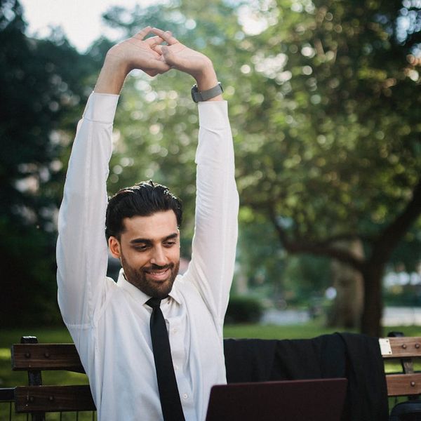 Person smiling and stretching gently outdoors in a park.